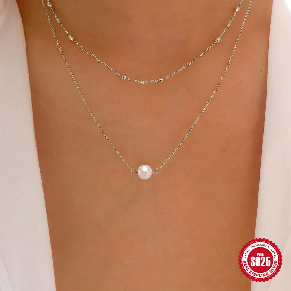 Close-up of a sterling silver double layer necklace with twin pearls on a ball bead chain, shown in gold tone.