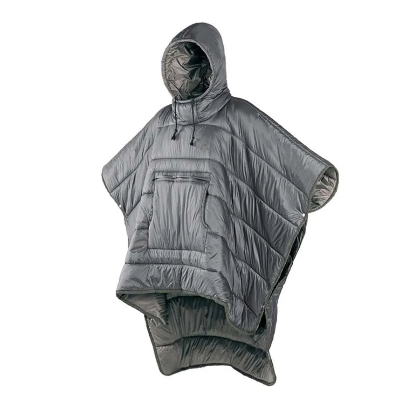 Adult wearing grey nylon cloak sleeping bag as wearable camping blanket outdoors