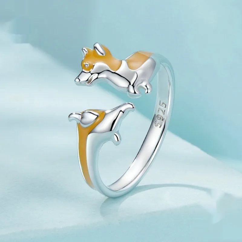 Silver-coloured cartoon corgi dog ring for women on a plain background.
