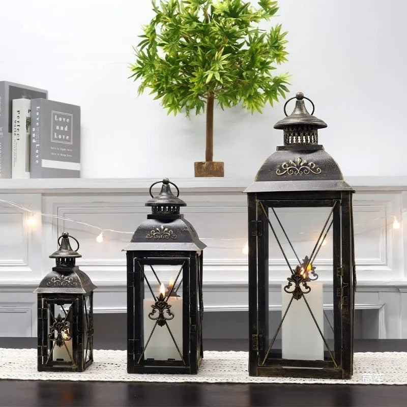 Black and white wrought iron floor-standing storm lantern with tempered glass panes for garden decoration.