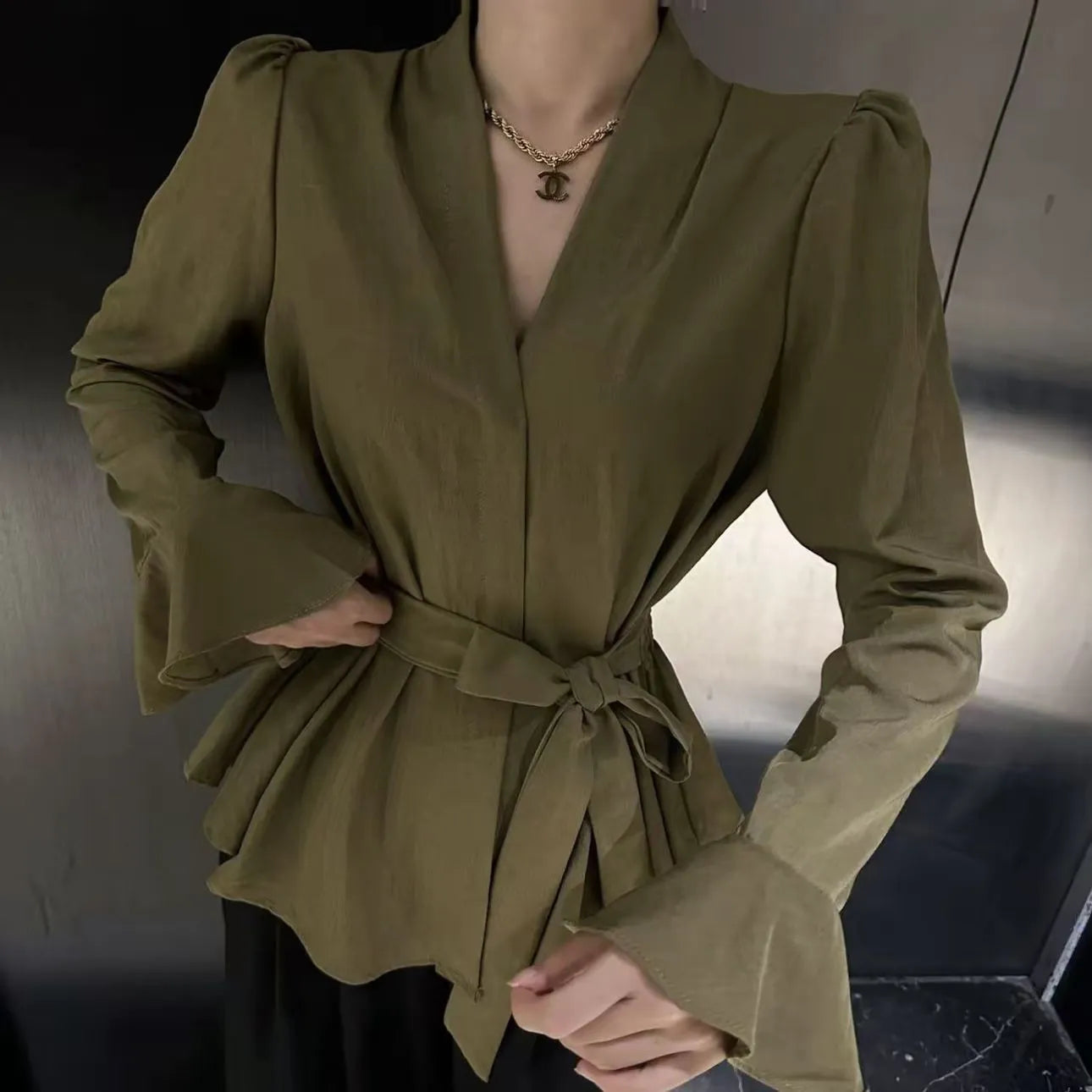 Women's black French-style shirt with irregular collar and tied waist detail featuring bell sleeves