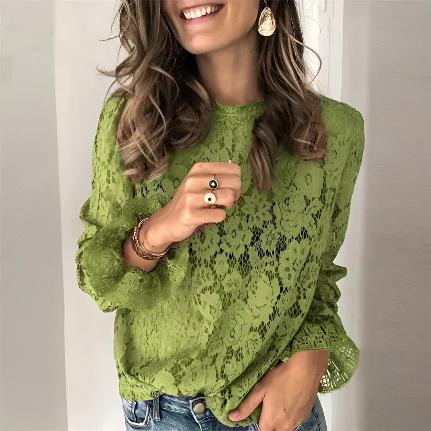 Women's green hollow lace shirt with round neck and long sleeves on a hanger
