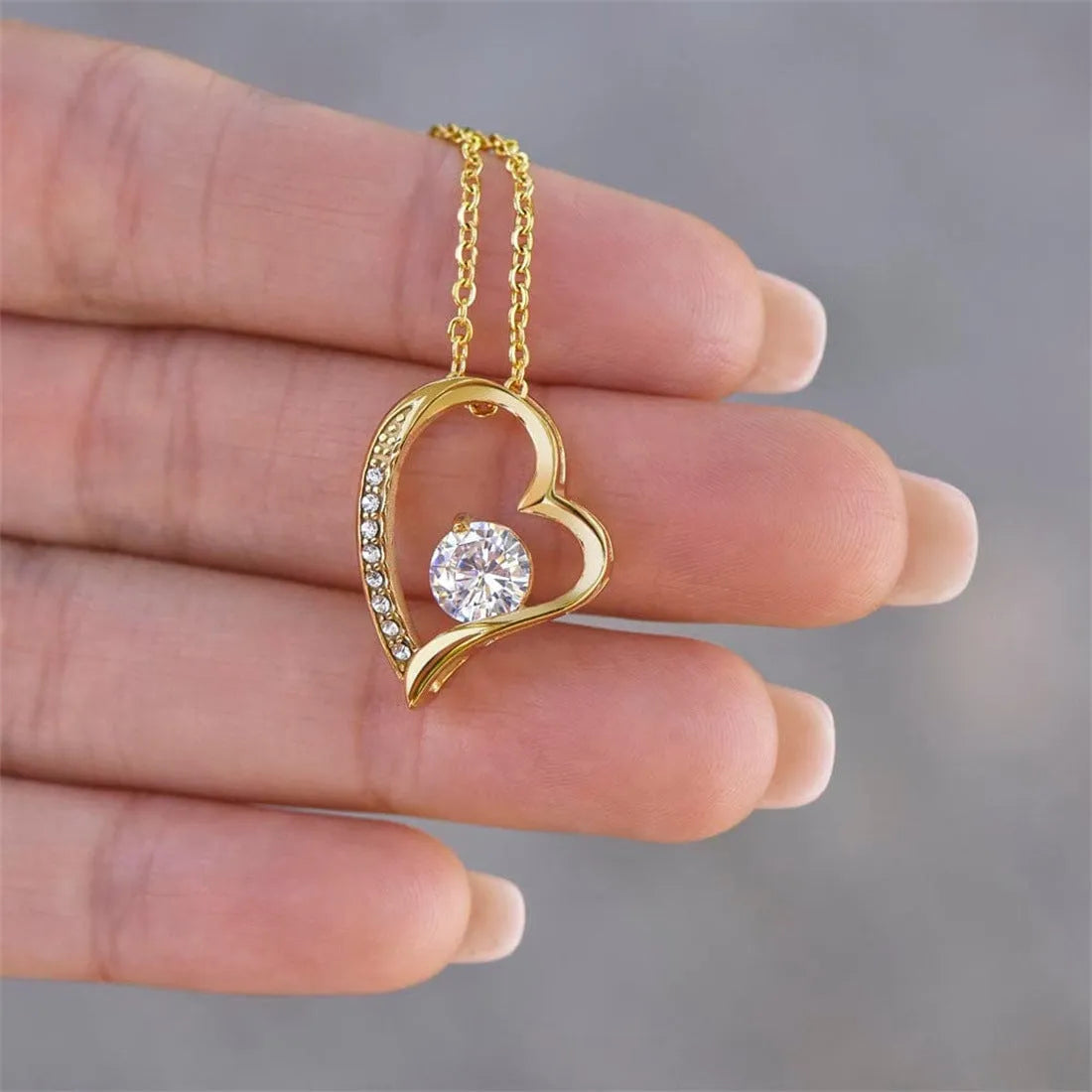 A hollow heart-shaped pendant necklace on a chain, presented in a gift box with a card.