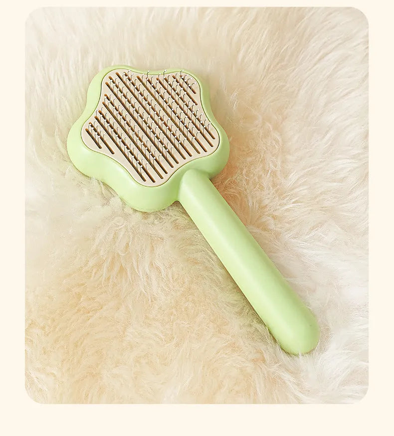 Green and yellow self-cleaning cat comb with stainless steel needles for pet grooming.