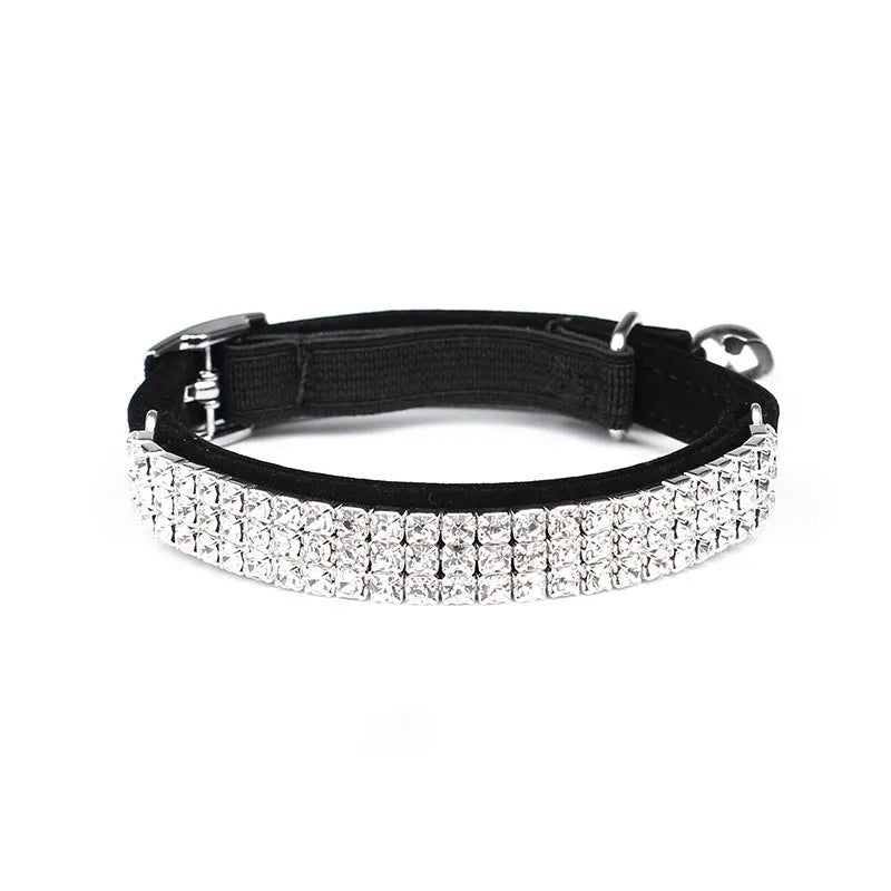 Close-up of a soft red velvet cat collar with a line of sparkling rhinestones and an adjustable buckle.