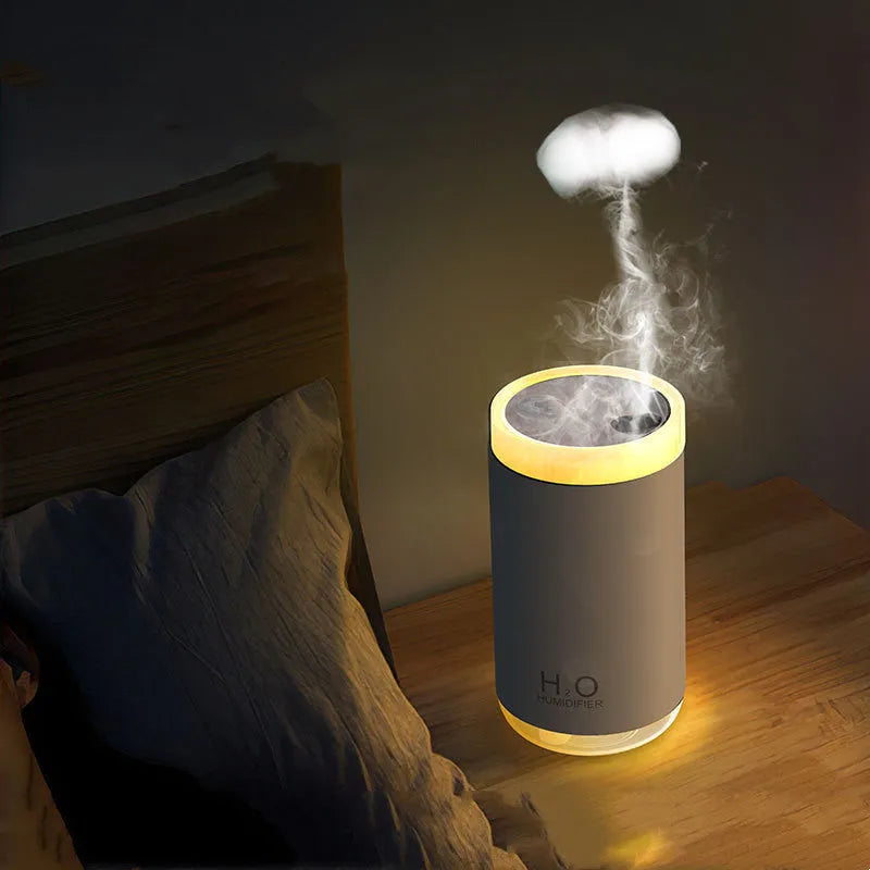 White jellyfish-shaped humidifier emitting smoke rings on a desk, with USB cable and warm glow.