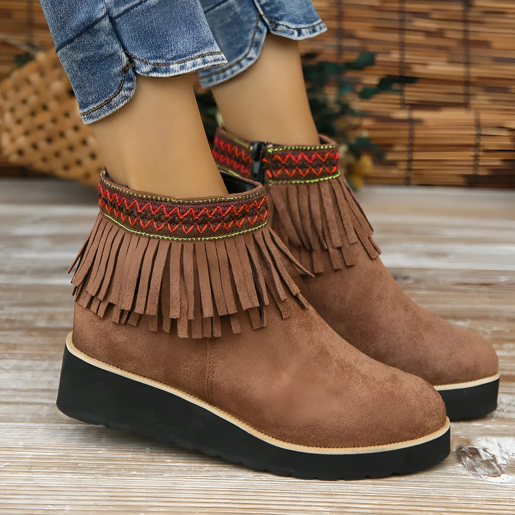 Women's suede ankle boot with wedge rubber sole, side zip, and tassel detail in dark brown.
