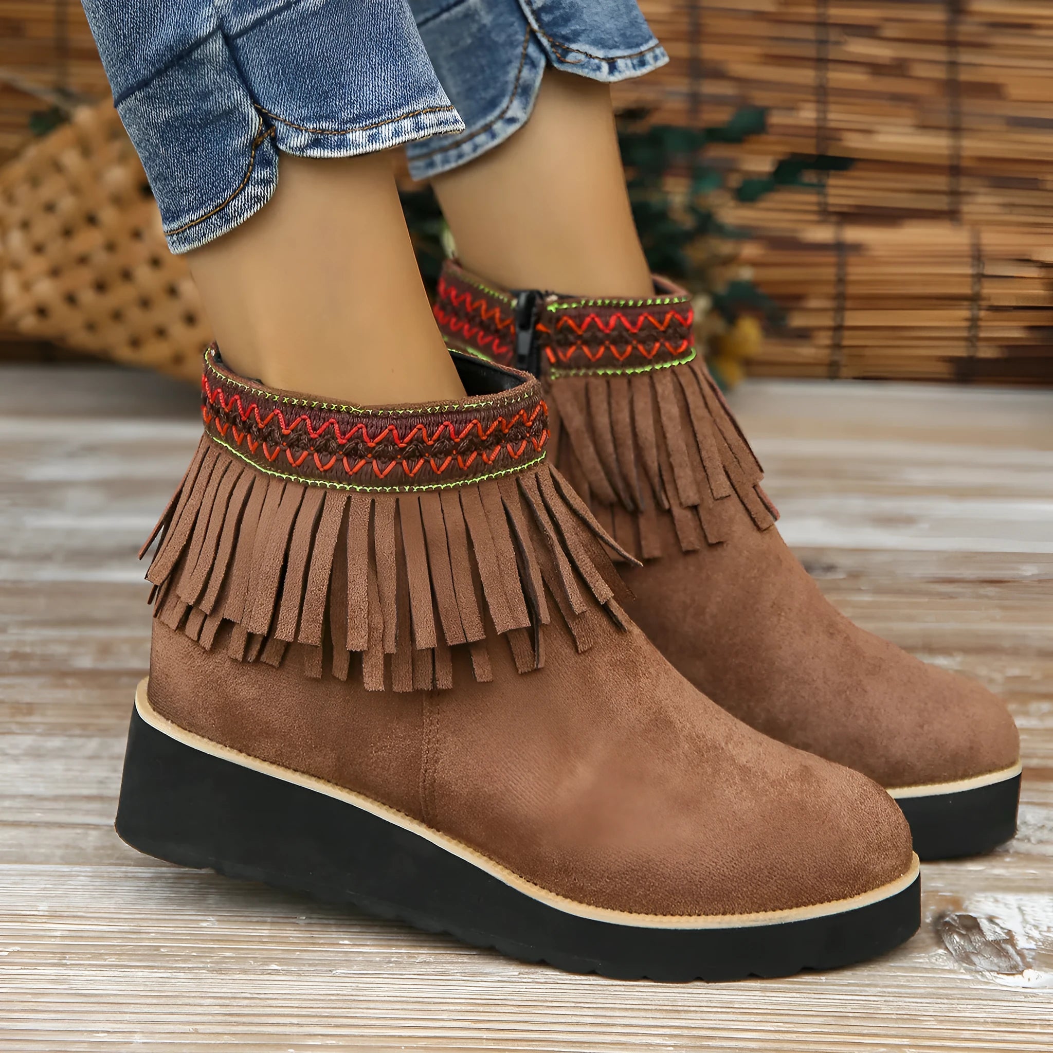 Women's suede ankle boot with wedge rubber sole, side zip, and tassel detail in dark brown.