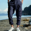 Men's loose-fit linen casual trousers with ankle-tied cuffs and multiple pockets in a solid colour.