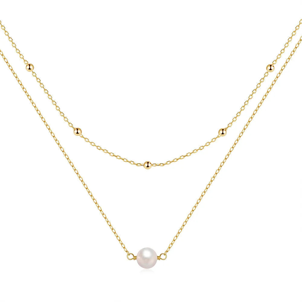 Close-up of a sterling silver double layer necklace with twin pearls on a ball bead chain, shown in gold tone.