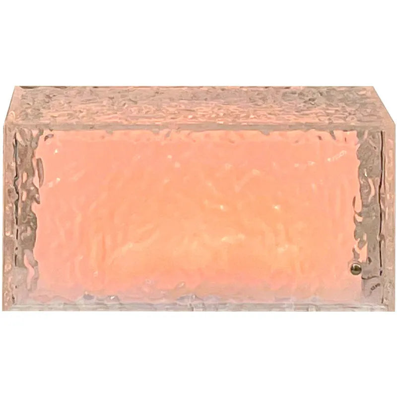 Geometric ice cube shaped clear acrylic LED night light on a table.