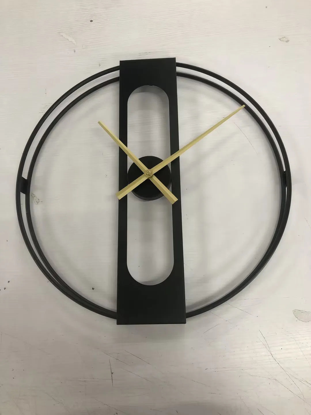 Round metal wall clock in black or gold, 50 cm diameter, on a white wall.