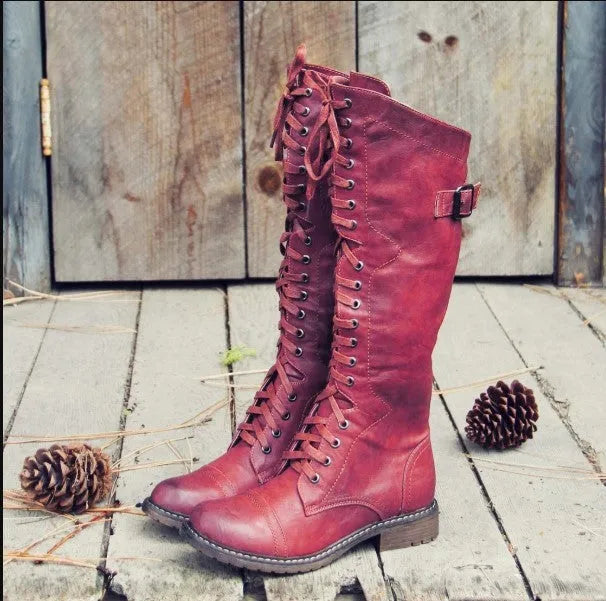 Women's brown ankle boots with a front cross strap and buckle fastening, shown on a white background.