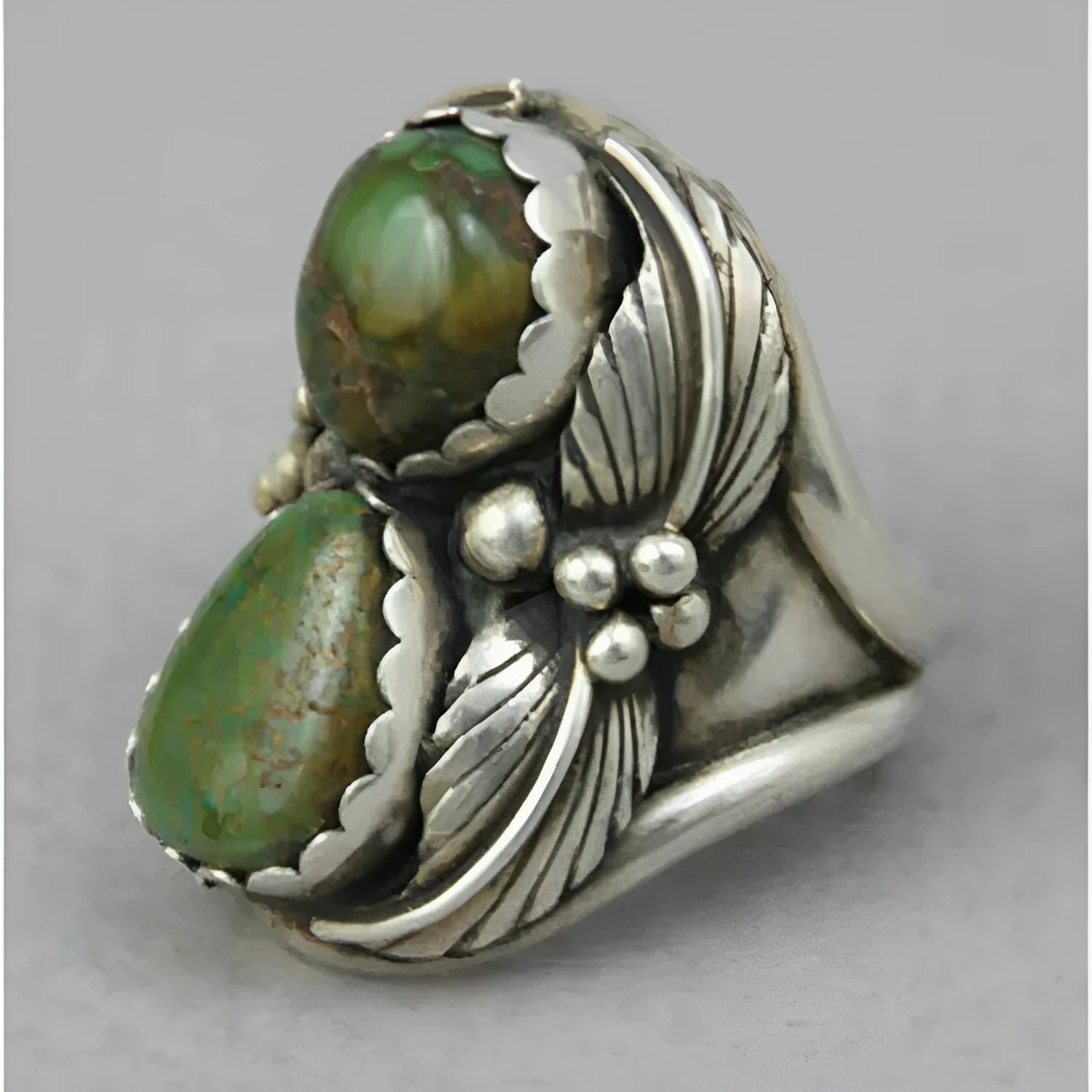 Close-up of a geometric alloy ring with a retro turquoise inlaid centre on a model's hand.