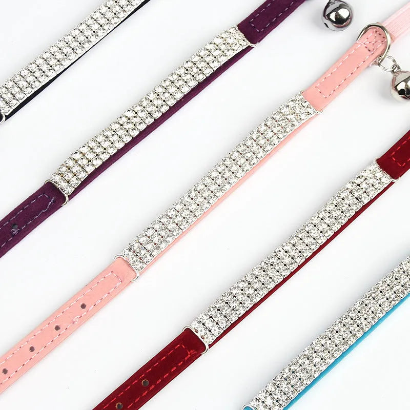 Close-up of a soft red velvet cat collar with a line of sparkling rhinestones and an adjustable buckle.