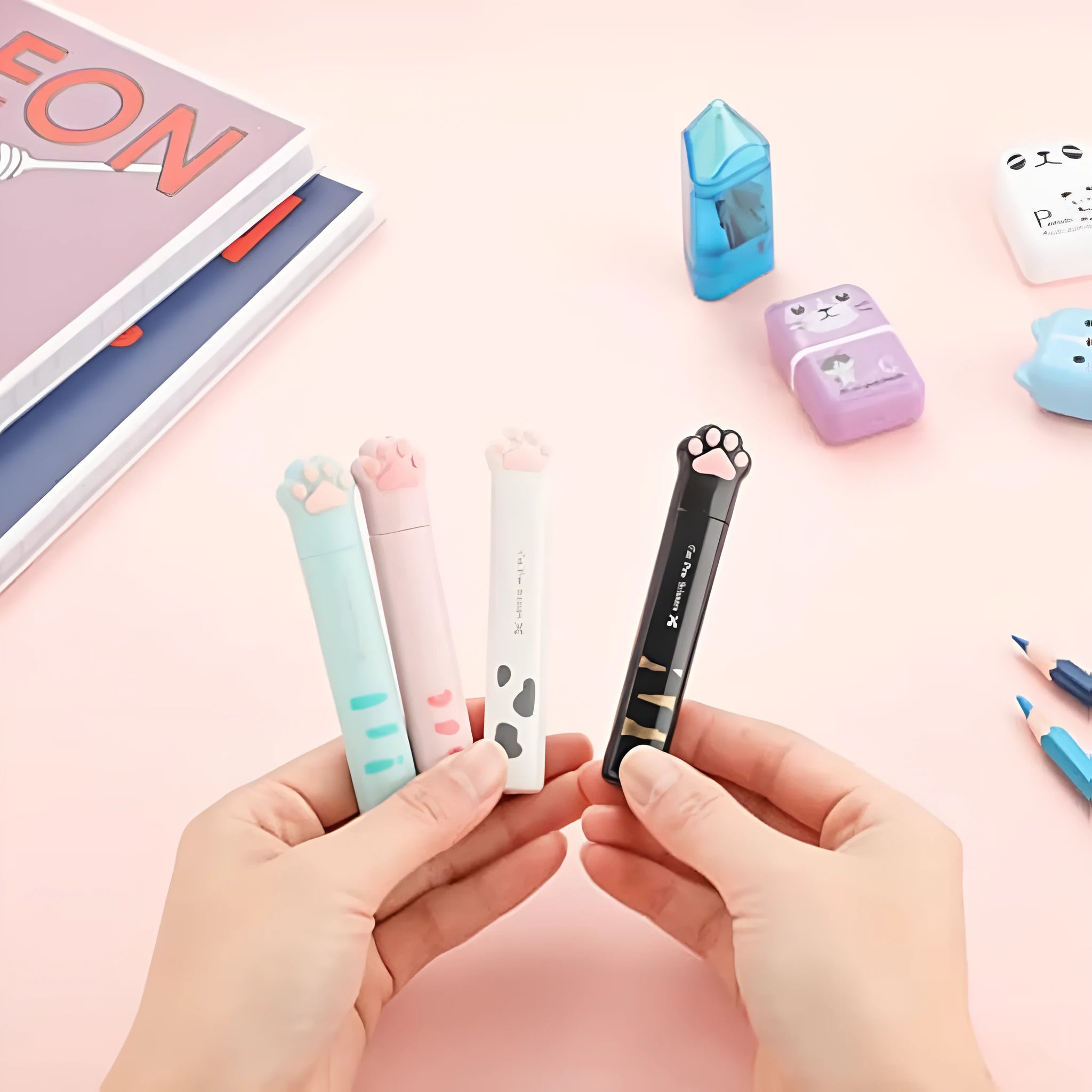 Set of four small folding scissors with cat paw handles in black, blue, pink, and white colours.