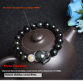 Natural black obsidian bracelet with 10mm beads on wrist, showing gold tone fastening option.