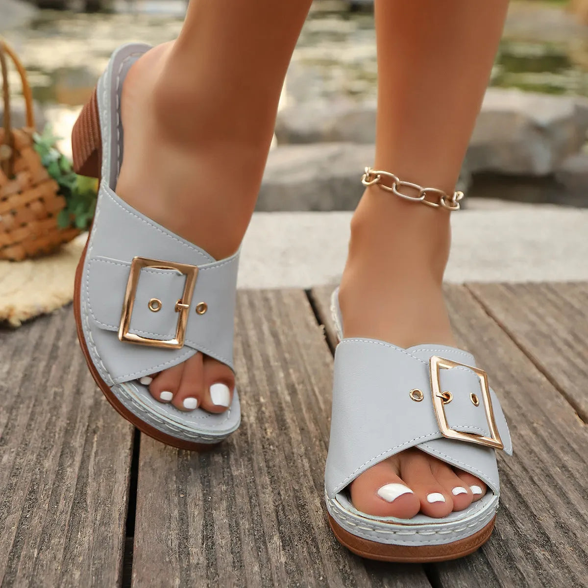 Women's black chunky heel slippers with a silver metal buckle and rubber sole on a light background.