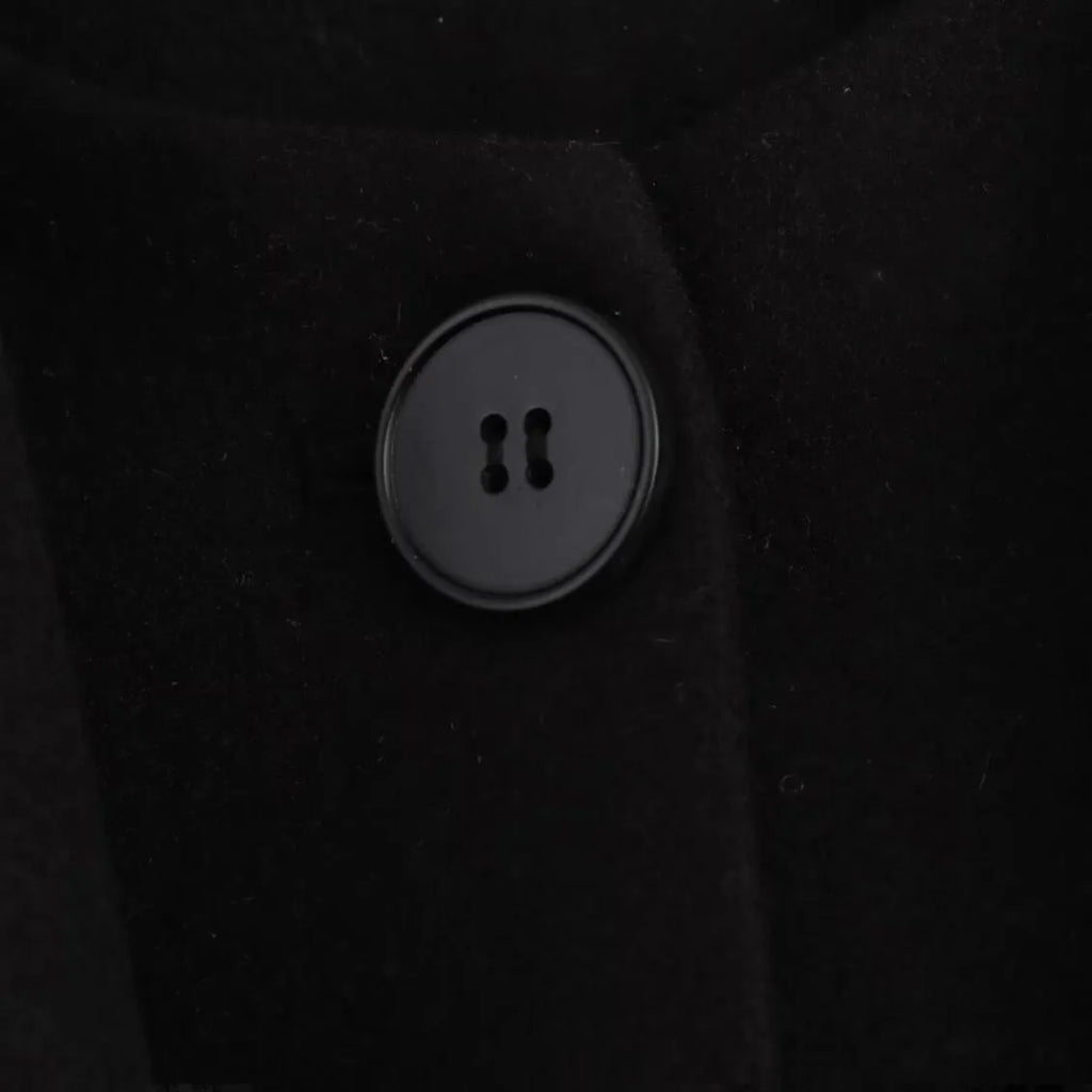 Women's long black overcoat with grey artificial fur collar, showing longline silhouette and pocket detail.