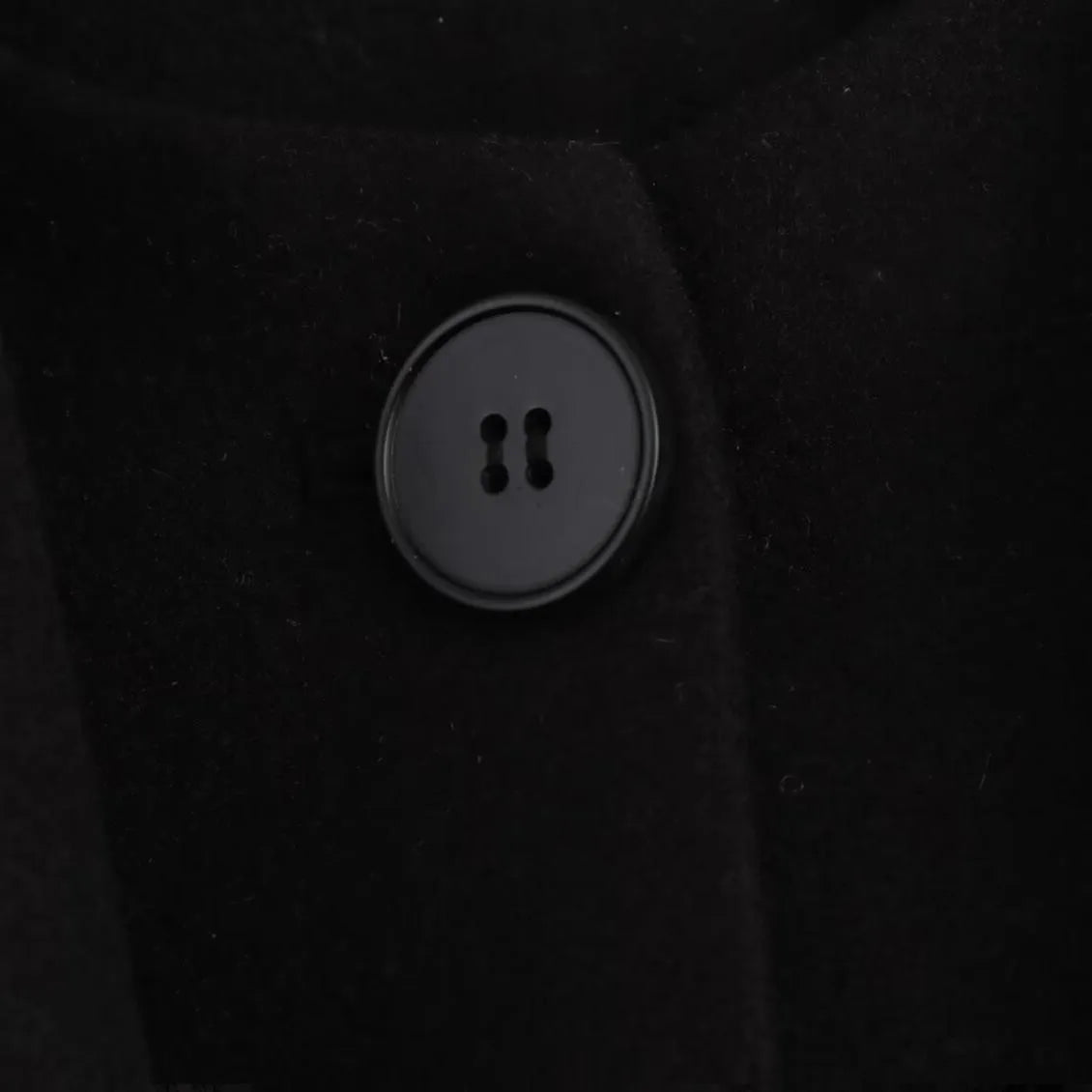 Women's long black overcoat with grey artificial fur collar, showing longline silhouette and pocket detail.