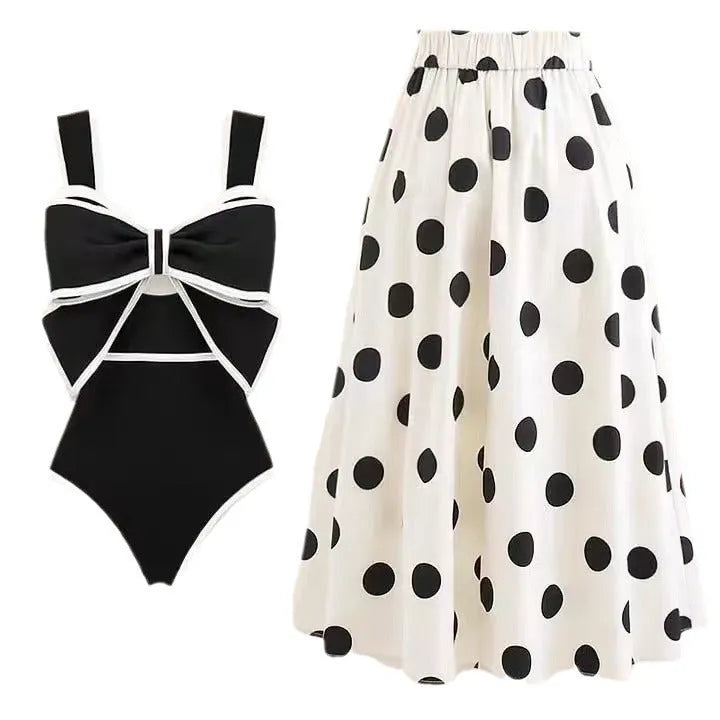 Women's black one-piece swimsuit with attached white skirt-style beach dress and a bow detail.