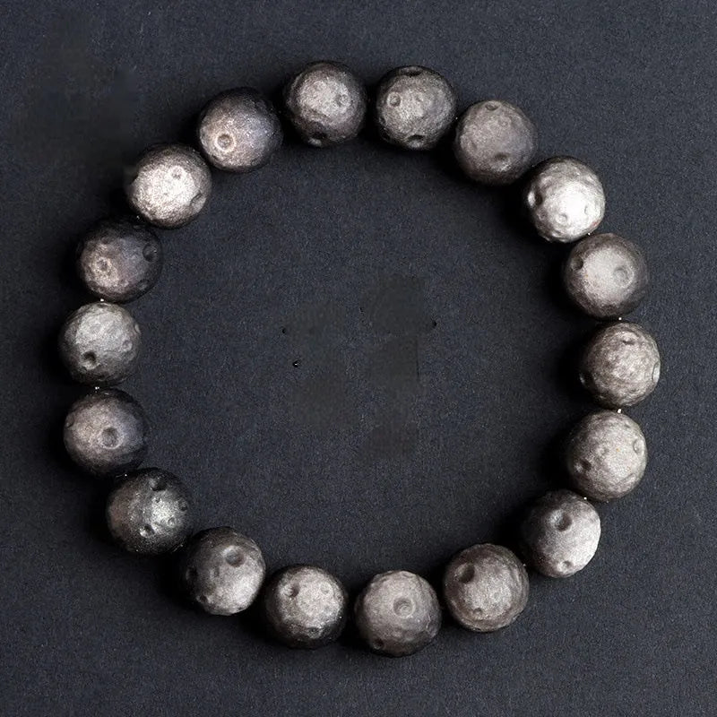 Natural obsidian crater ball bracelet showing textured beads in silver stone or golden obsidian colour on a wrist.