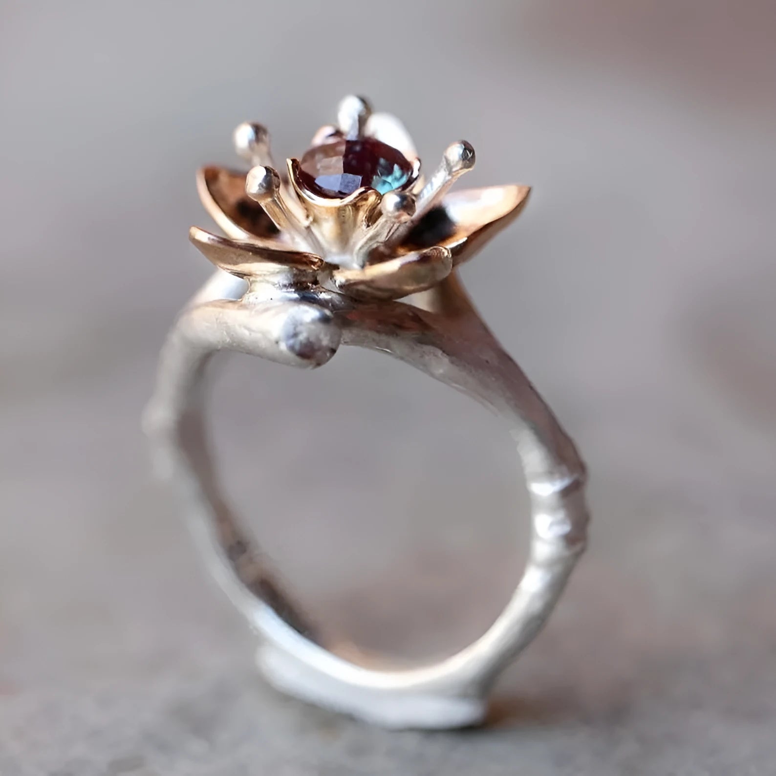 Silver two-tone alloy ring with geometric floral design on a white background.