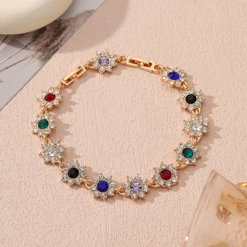 Electroplated zinc alloy bracelet with flower-shaped coloured gems in gold or silver tone.