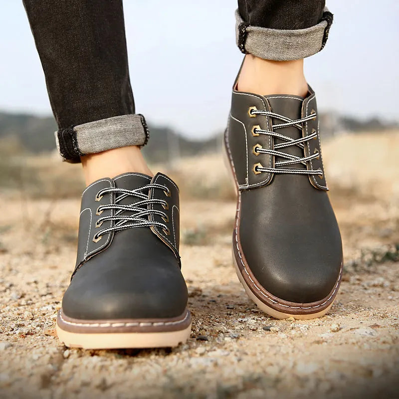 Men's black mid-top waterproof work boots with a flat rubber sole.