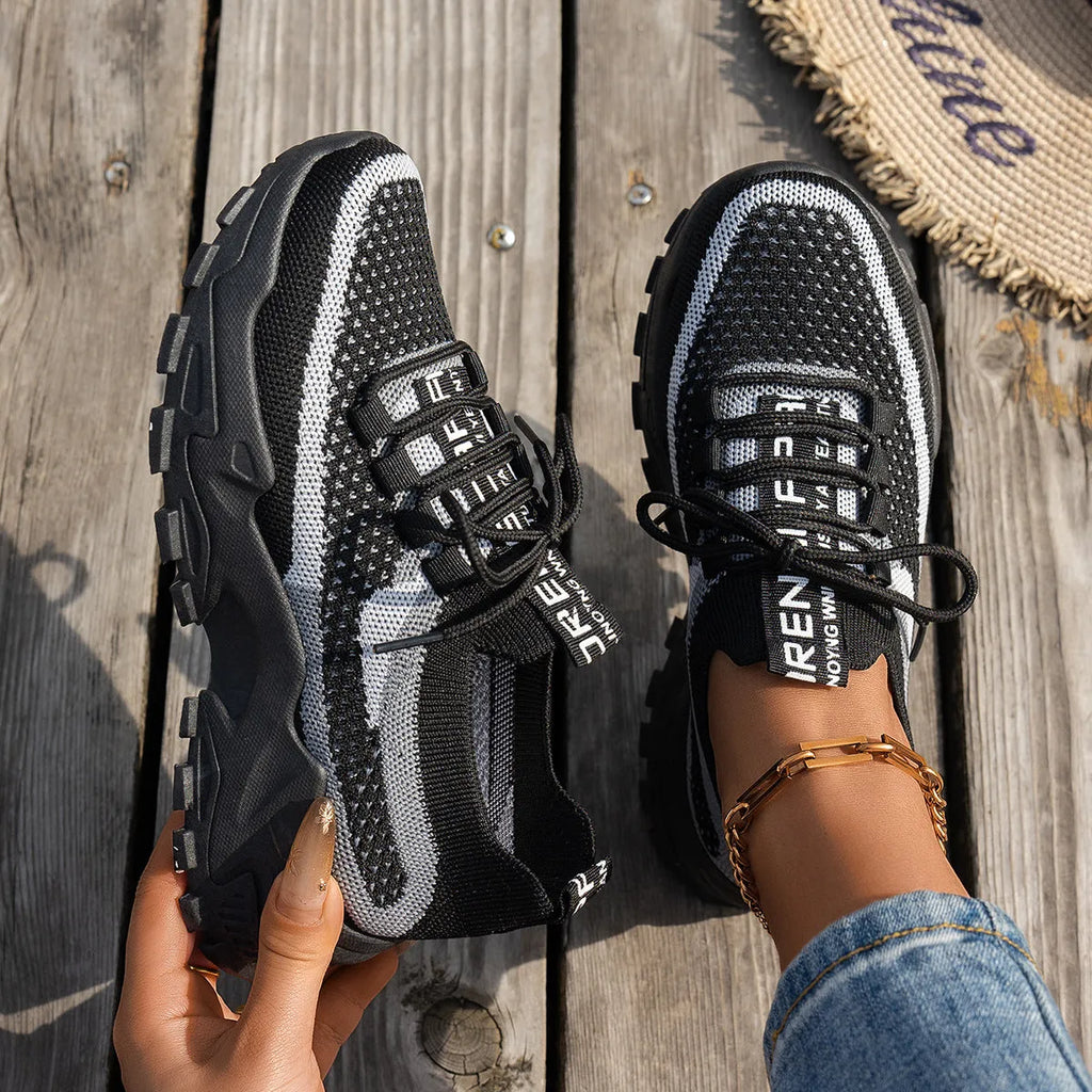 Women's Flyknit mesh lace-up sneakers in a grey colourway showing round toe and low profile.