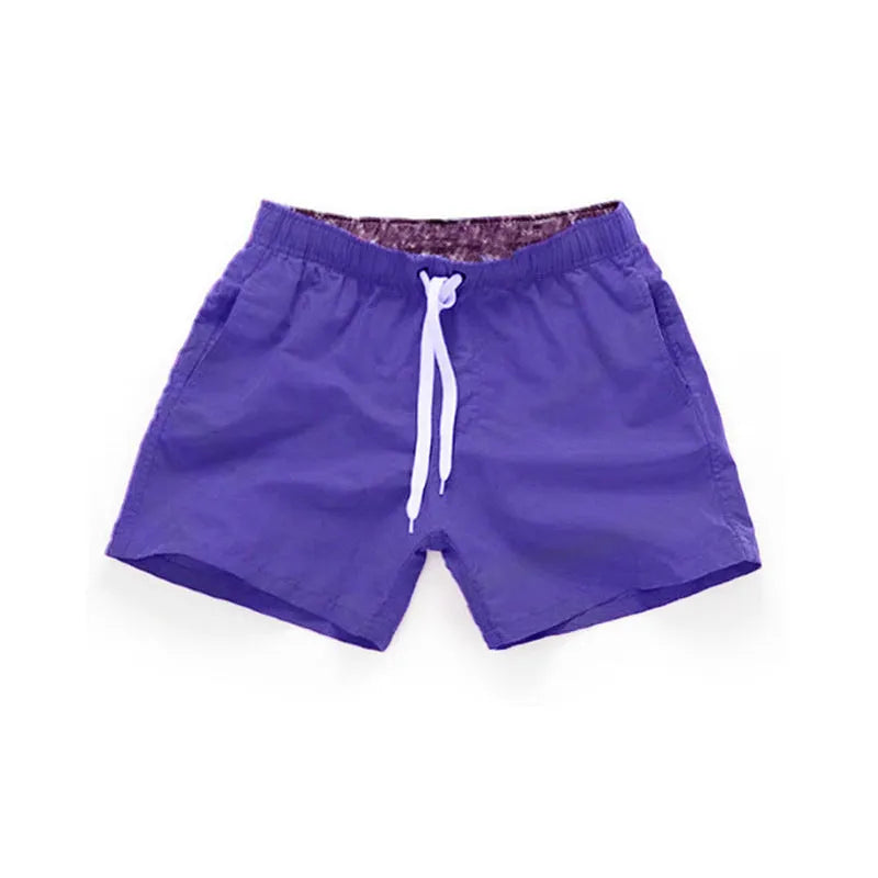 Men's straight-leg polyester beach shorts on a hanger, showing the classic fit and available in multiple solid colours.