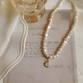 Adjustable vintage pearl necklace with geometric design on a grey background.