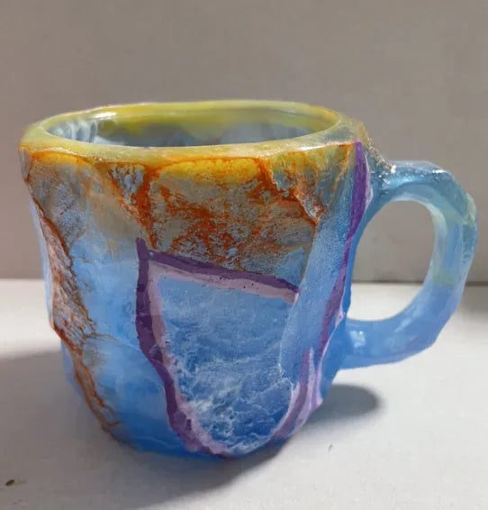 Purple and blue resin coffee mug with crystal texture and handle on wooden table