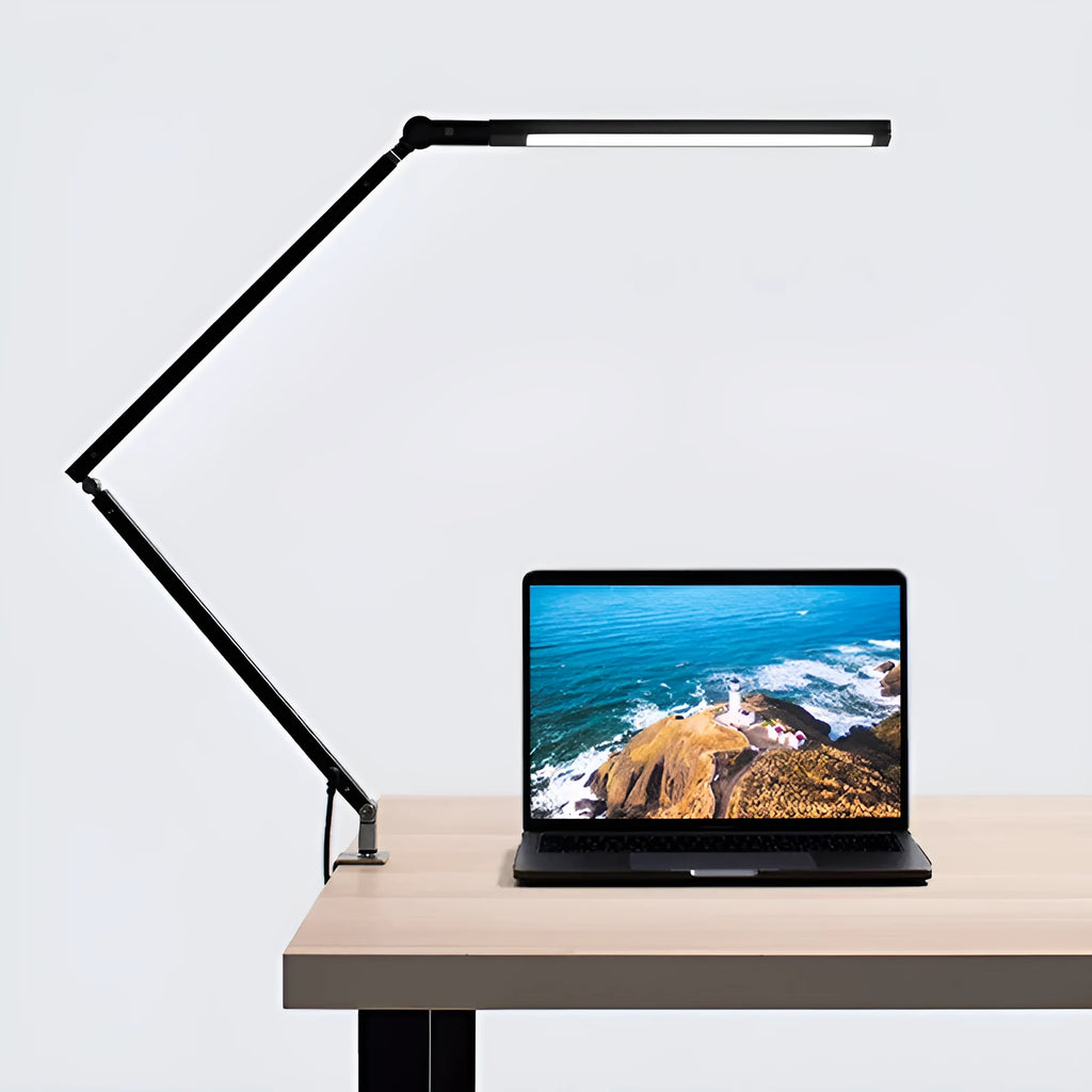 Black LED clip desk lamp with adjustable folding arm and remote control on a wooden desk.