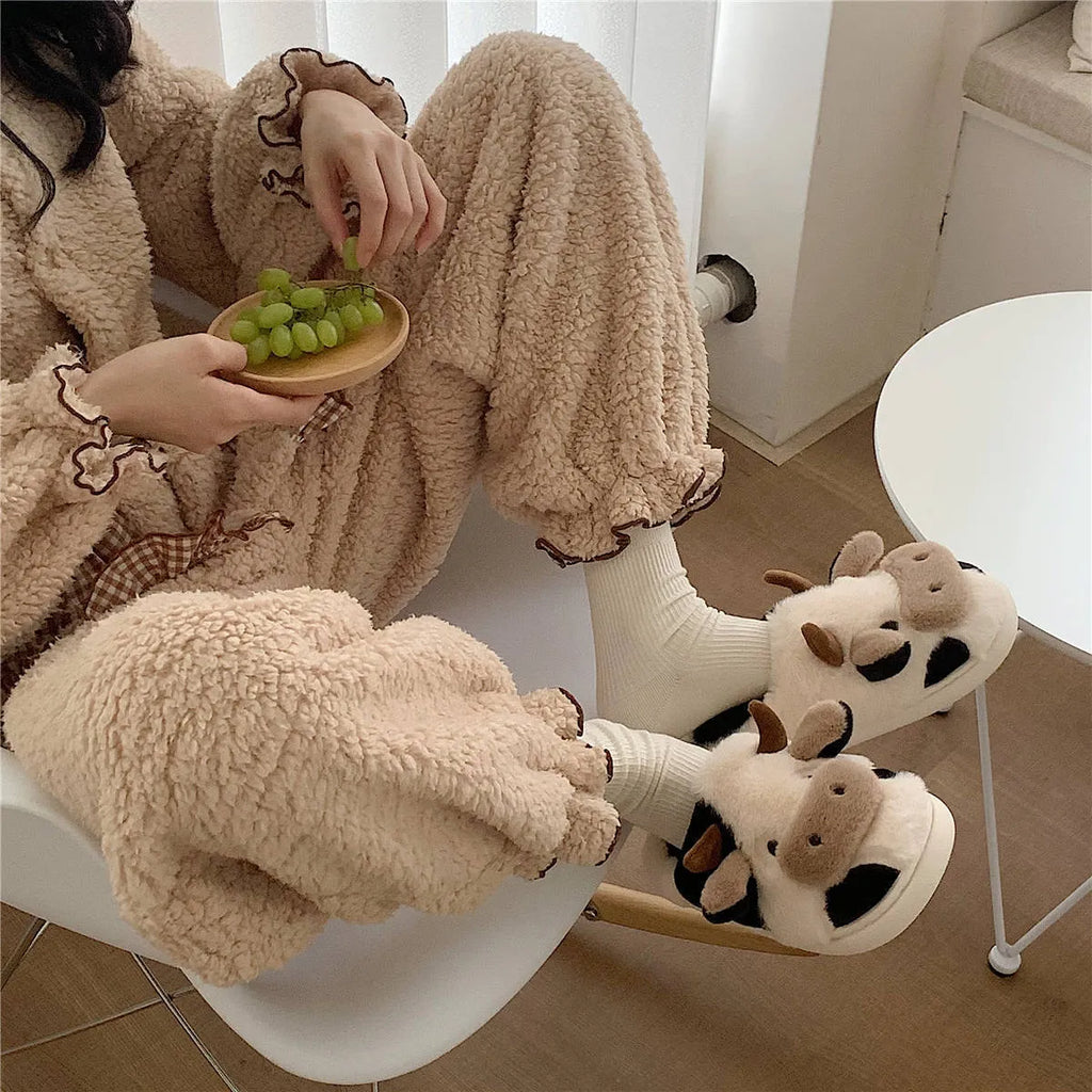 White and coffee coloured cow animal slippers for women with a plush exterior and non-slip sole.