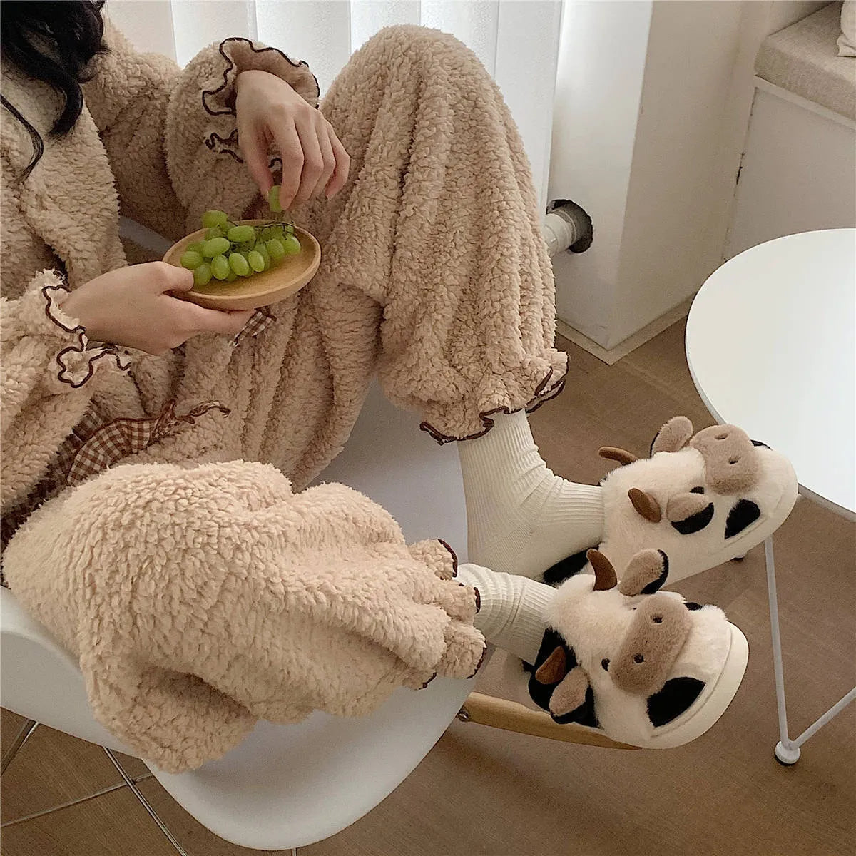 White and coffee coloured cow animal slippers for women with a plush exterior and non-slip sole.