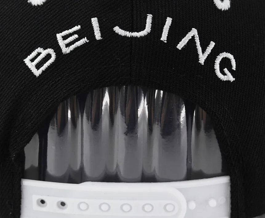 Black cotton baseball hat with white embroidered letters on the front, showing the dome crown shape.