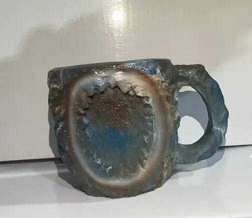 Purple and blue resin coffee mug with crystal texture and handle on wooden table