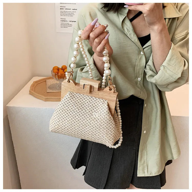 Women's woven straw shoulder bag with pearl chain strap and zippered interior pockets in beige, black, or khaki