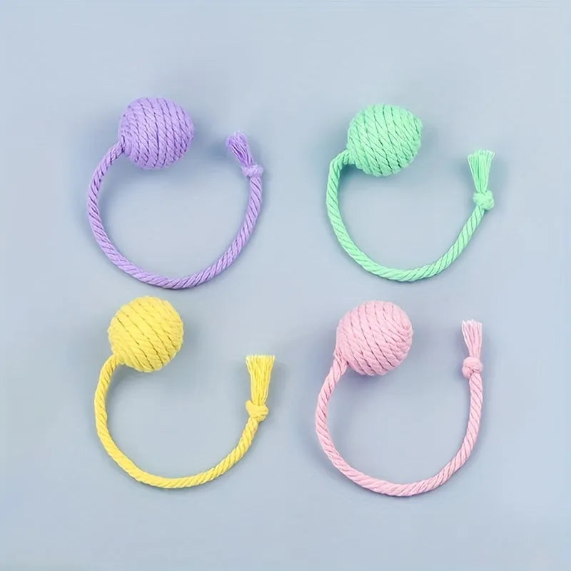 Green and pink plastic cat toy balls with ropes and internal bells.
