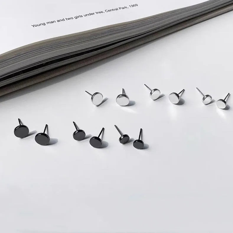 A pair of small, round, flat sterling silver stud earrings for cartilage piercing on a plain background.