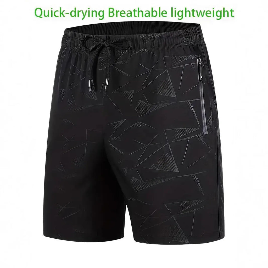 Man wearing loose fit black printed polyester sports shorts with elastic waistband on a beach.
