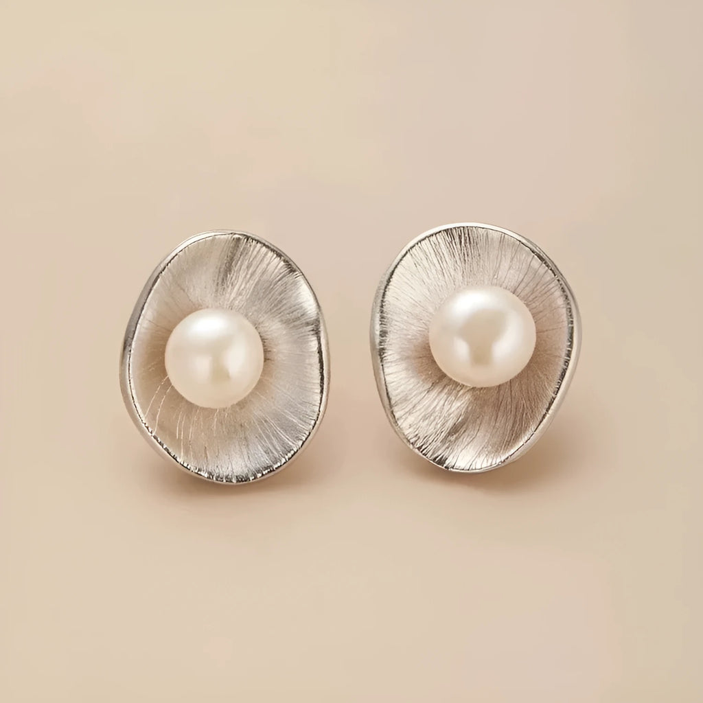A pair of silver geometric pearl ear studs with gold electroplated finish on needle posts.