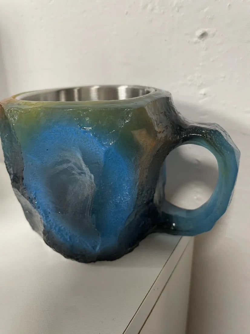 Purple and blue resin coffee mug with crystal texture and handle on wooden table